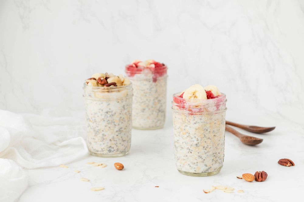 Three jars of overnite oats with berries and bananas