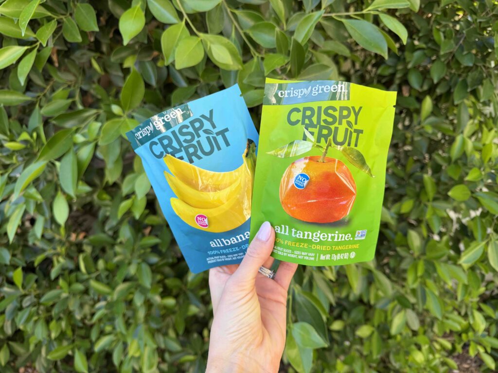 A hand holding a bag of banana and mandarin Chrispy fruit